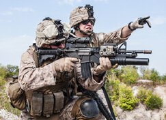 two soldiers, one sighting down a gun and the other pointing