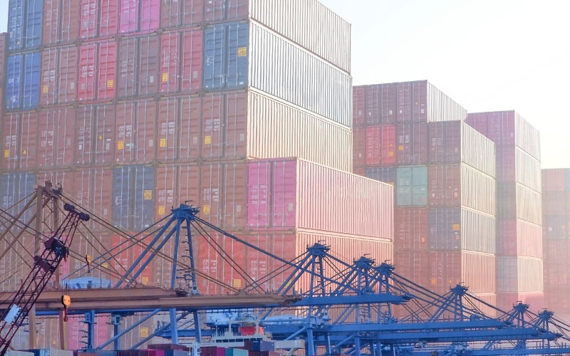 several stacks of shipping containers and cranes to move them