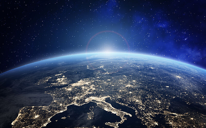 View of Earth against a space backdrop with city lights and natural features