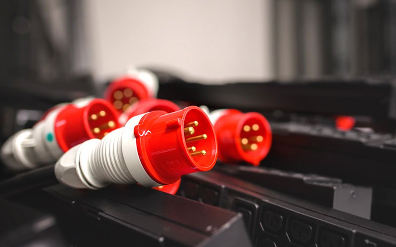 Red industrial circular connectors placed in an equipment rack.