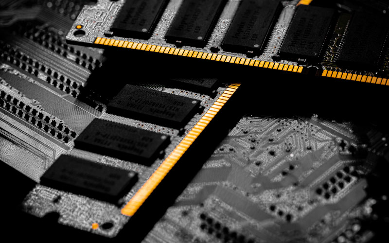 Close-up of RAM sticks with black chips and gold connector pins on a motherboard.