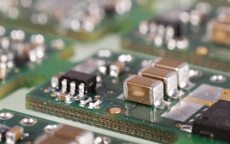Close up of a green circuit board with various electronic components.