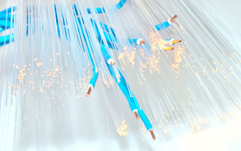 Blue wires with exposed copper cores among glowing fiber-optic strands.
