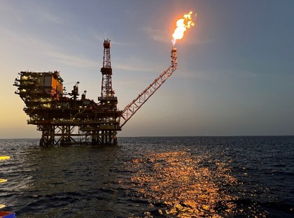 An oil rig stands in the ocean at dusk.